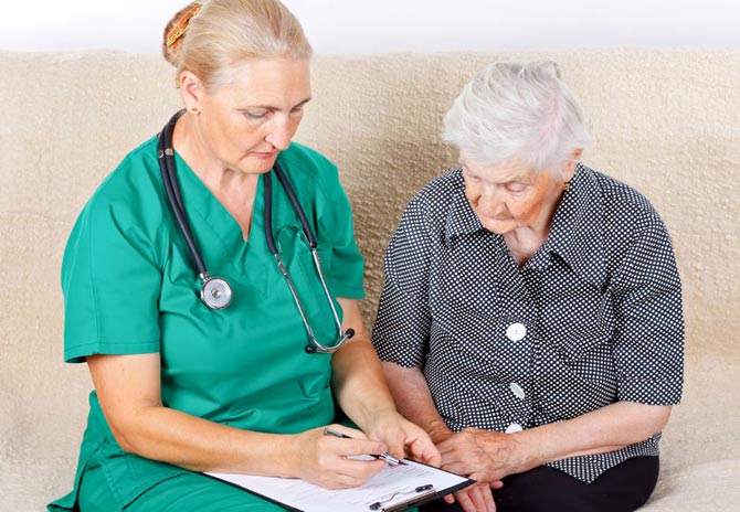 Aging woman reviewing paperwork with female medical staff